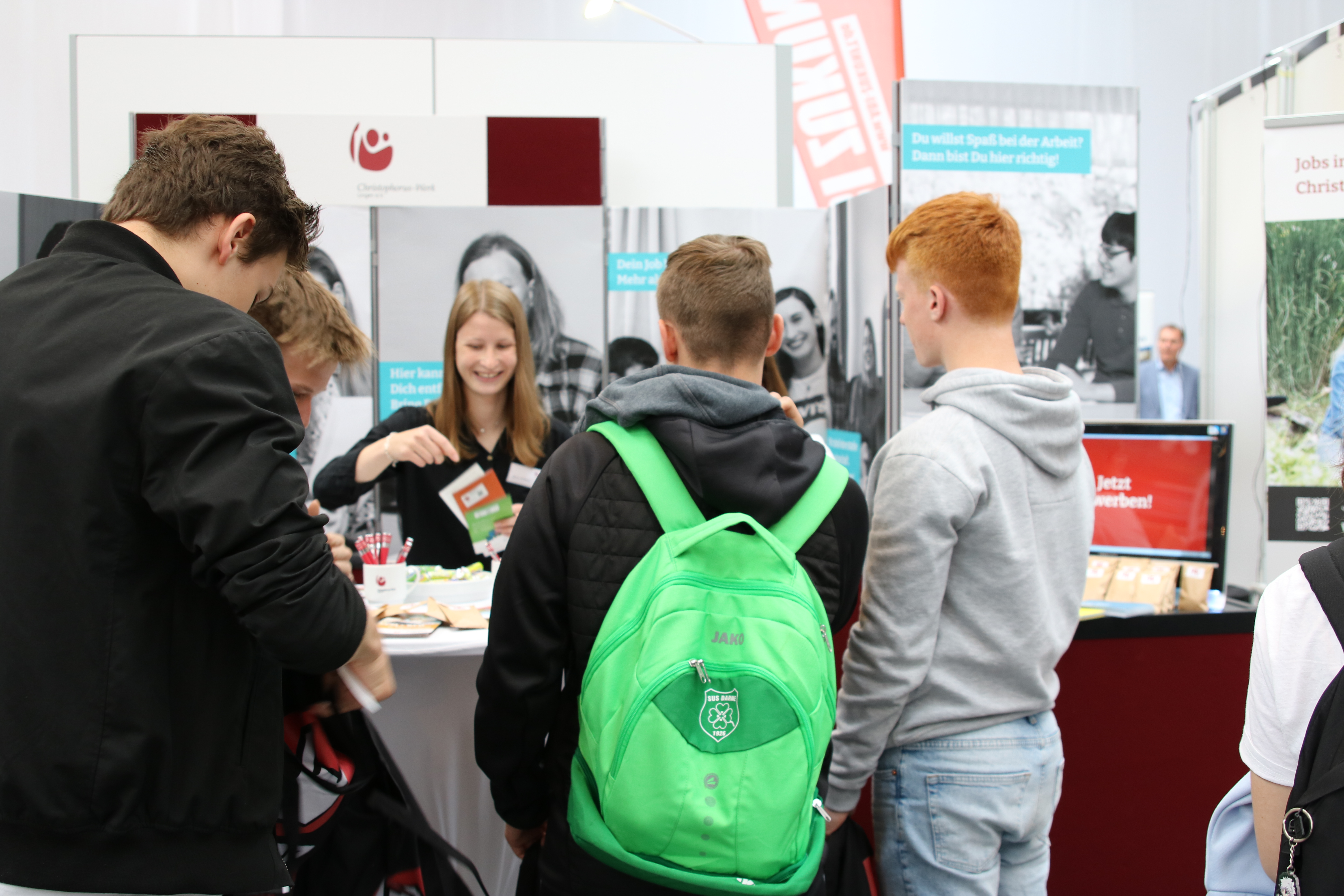 Junge Menschen lassen sich am Messestand des Christophorus-Werkes Lingen beraten.